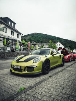 Parked luxury sports cars on a scenic street with hillside view.