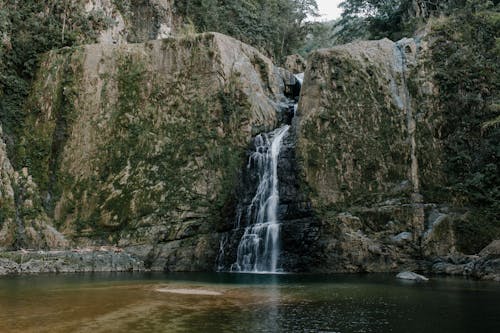 Fast waterfall between rough mountains near pure pond