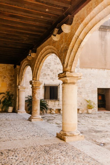 Aged stone house exterior with arches and colonnade on rough pavement in city in daylight