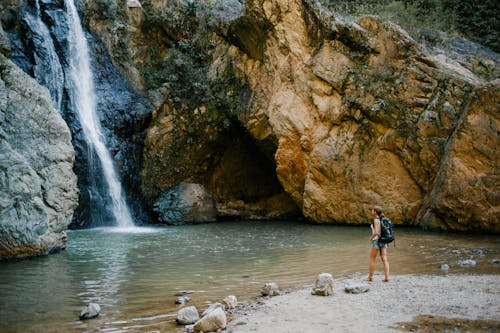 Backpacker Anonyme Contemplant Une Cascade Rapide Dans Les Montagnes Près De L'étang