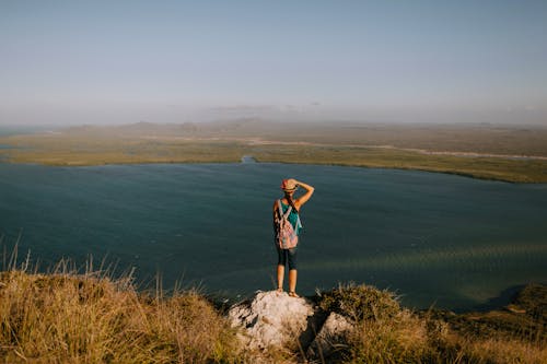 Anonymous traveler contemplating river from mount on foggy day