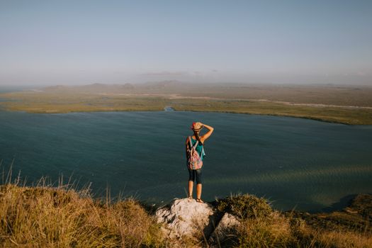 一位背着背包的女性旅行者正在欣赏多米尼加共和国风景优美的湖泊和景色