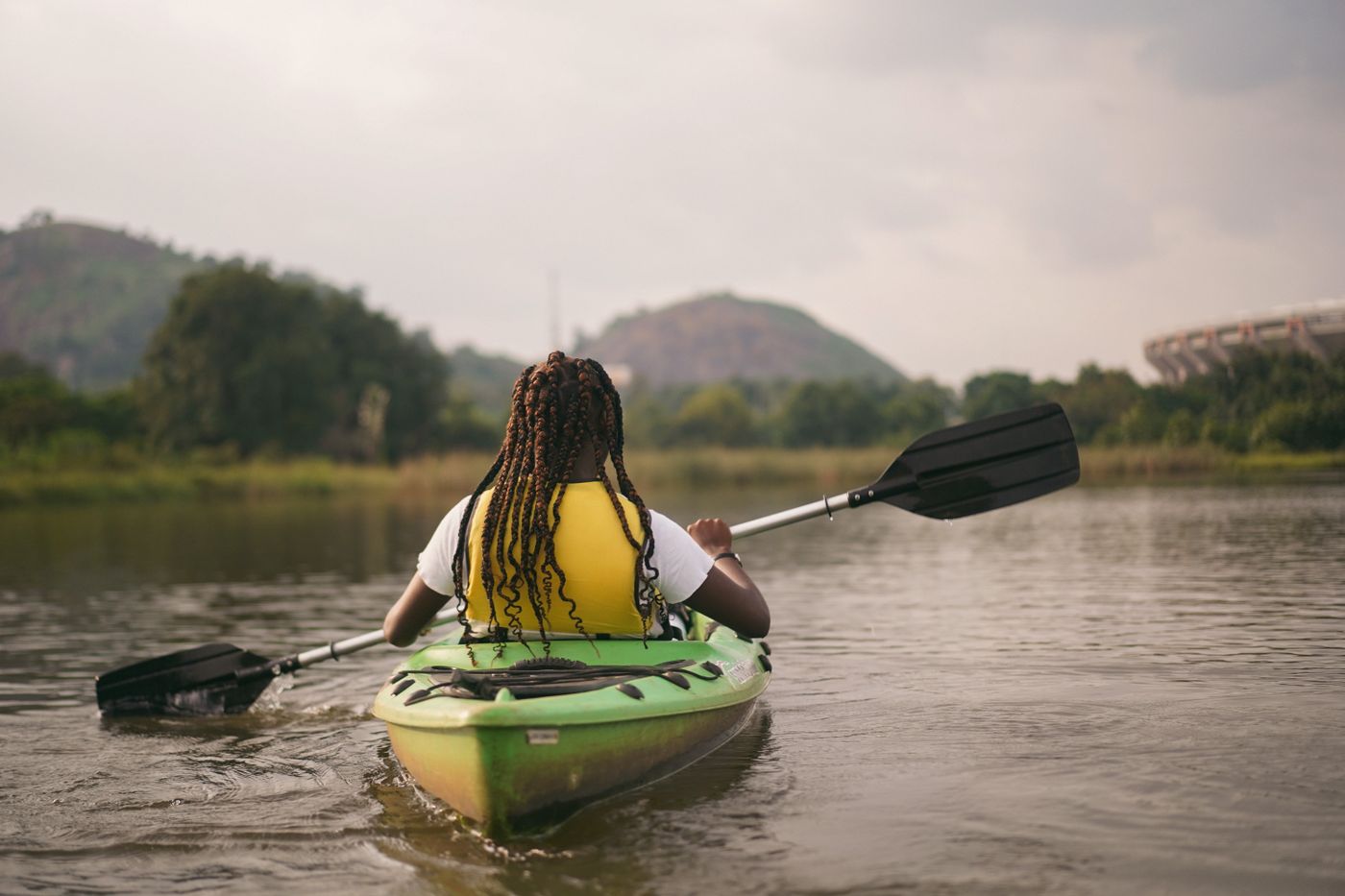 Person wearing a life jacket while paddling a green kayak