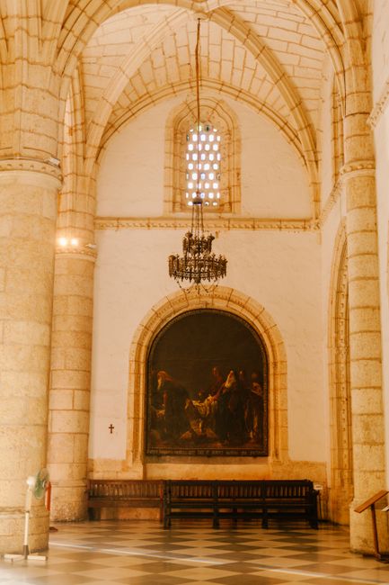 Aged stone cathedral interior with geometric vault above chandelier and floor near mural in sunlight