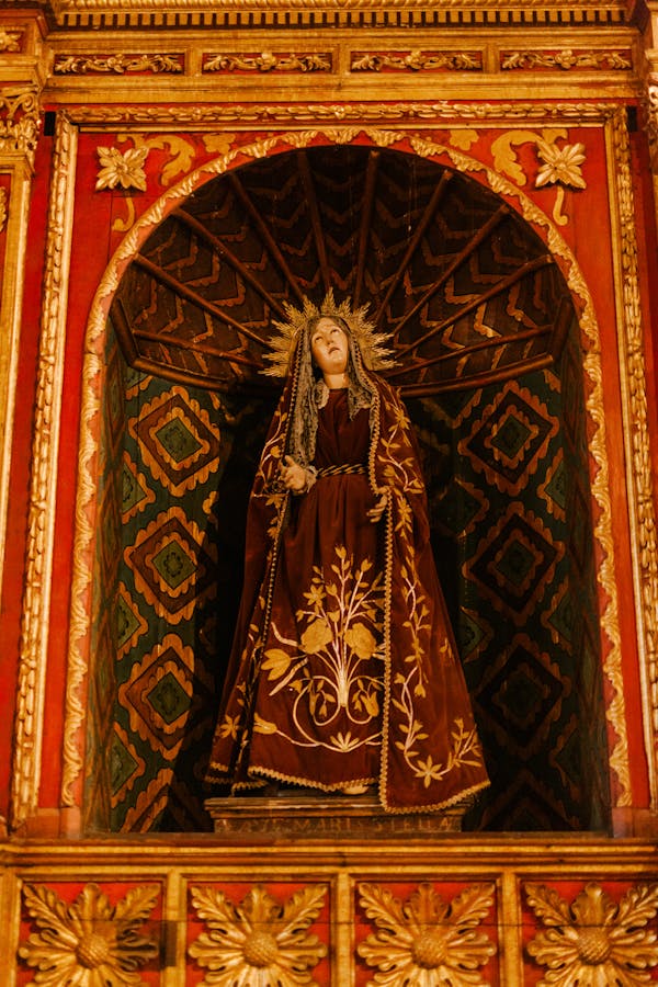 From below of bright aged altar with decor and figure of Virgin in church