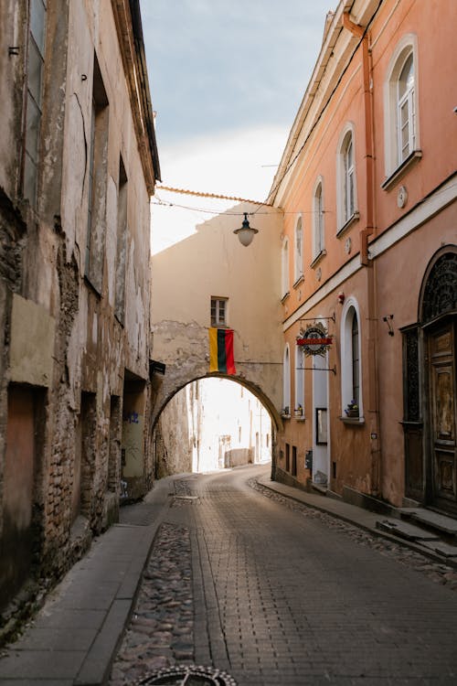 Exterior of old concrete weathered houses on narrow street with arch on sunny day