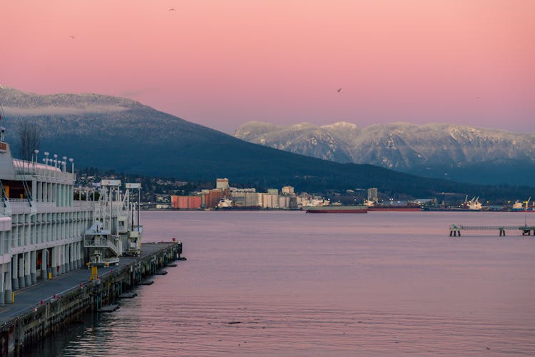 Pink Sunset Over Waterfront City And Mountains