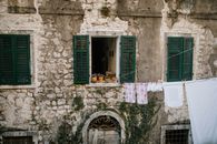 Exterior of aged house with potted plants on window and rope with clothes