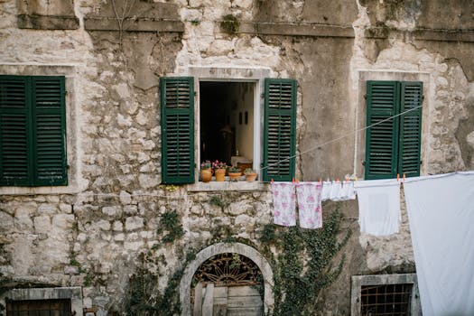 Charming stone house facade in Montenegro with plants and clothes drying outside.