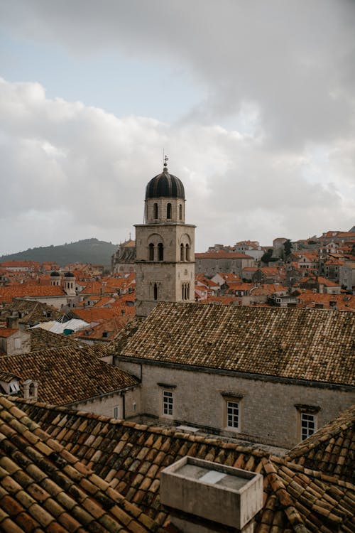 Residential buildings located around old tower of architectural monument Catholic church of Croatia under cloudy sky