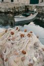 High angle of fishing nets with buoys tangled in heap placed on pier near boat