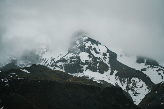 阴天时，崎岖的山脉岩石上覆盖着积雪，山峰则笼罩在浓雾之中