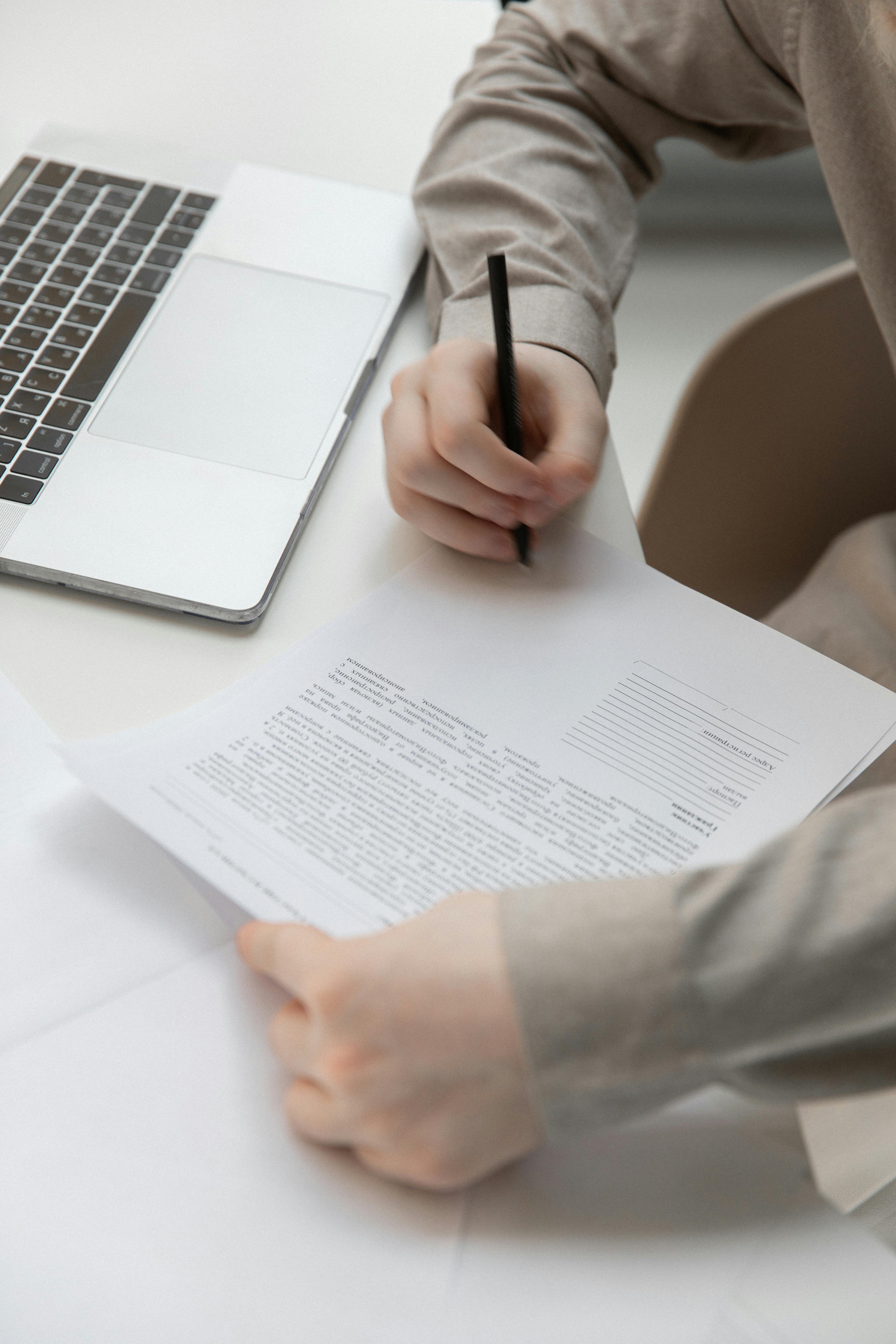 faceless male worker with paper document near laptop on desk