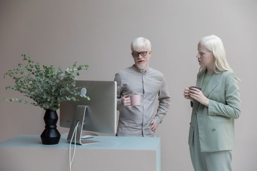 Albino coworkers standing near computer in office