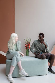 Two diverse colleagues engage in a friendly conversation in a modern office setting.