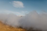 Scenery of dense gray clouds covering spacious mountainous valley against clear blue sky