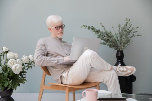 Busy albino man browsing laptop in room