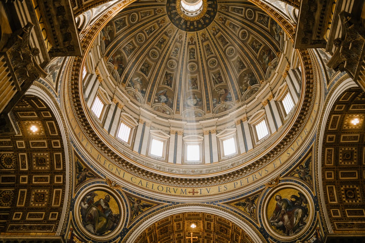 Low angle impressive design of dome with fresco paintings and golden ornamental elements in famous Catholic Saint Peters Basilica in Rome