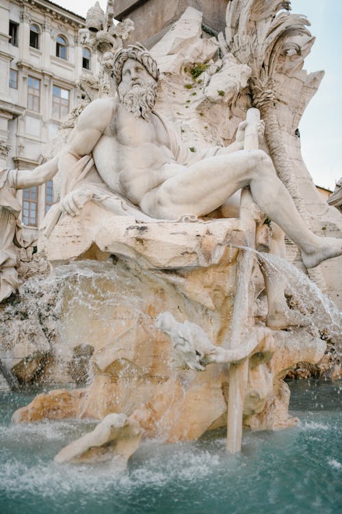 White marble Fountain of Four Rivers showing river god located in Rome on clear day