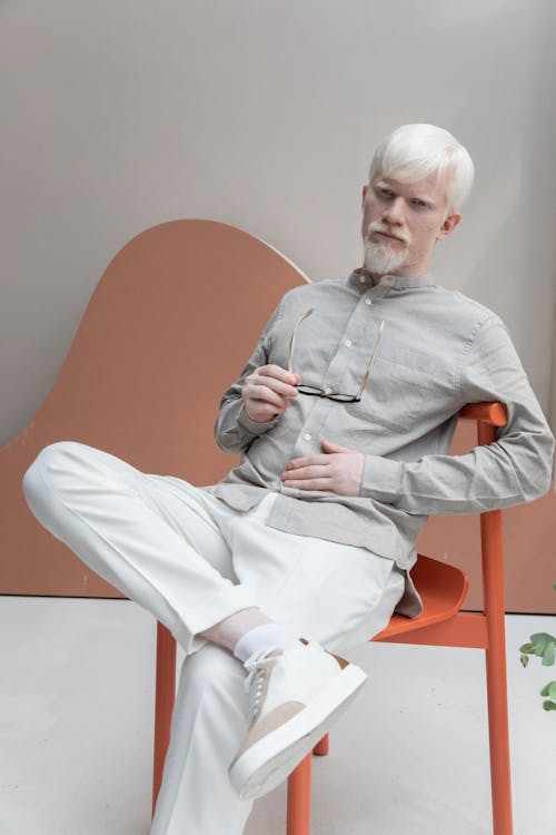 Albino man sitting on chair in room