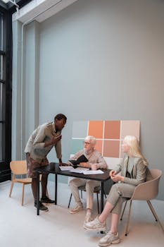 Diverse group of businesspeople collaborating around a table discussing creative projects with a color palette.