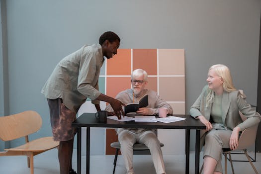 Group of multiethnic coworkers in casual clothes gathering around table with documents and talking about new project while working in modern office