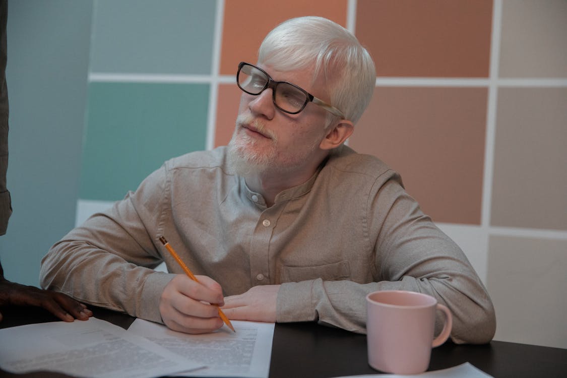 Free Albino man signing documents in office Stock Photo