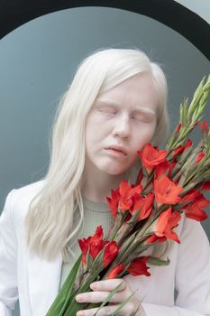 房间里，一位迷人的女模特闭着眼睛，手里拿着一束鲜红的花朵