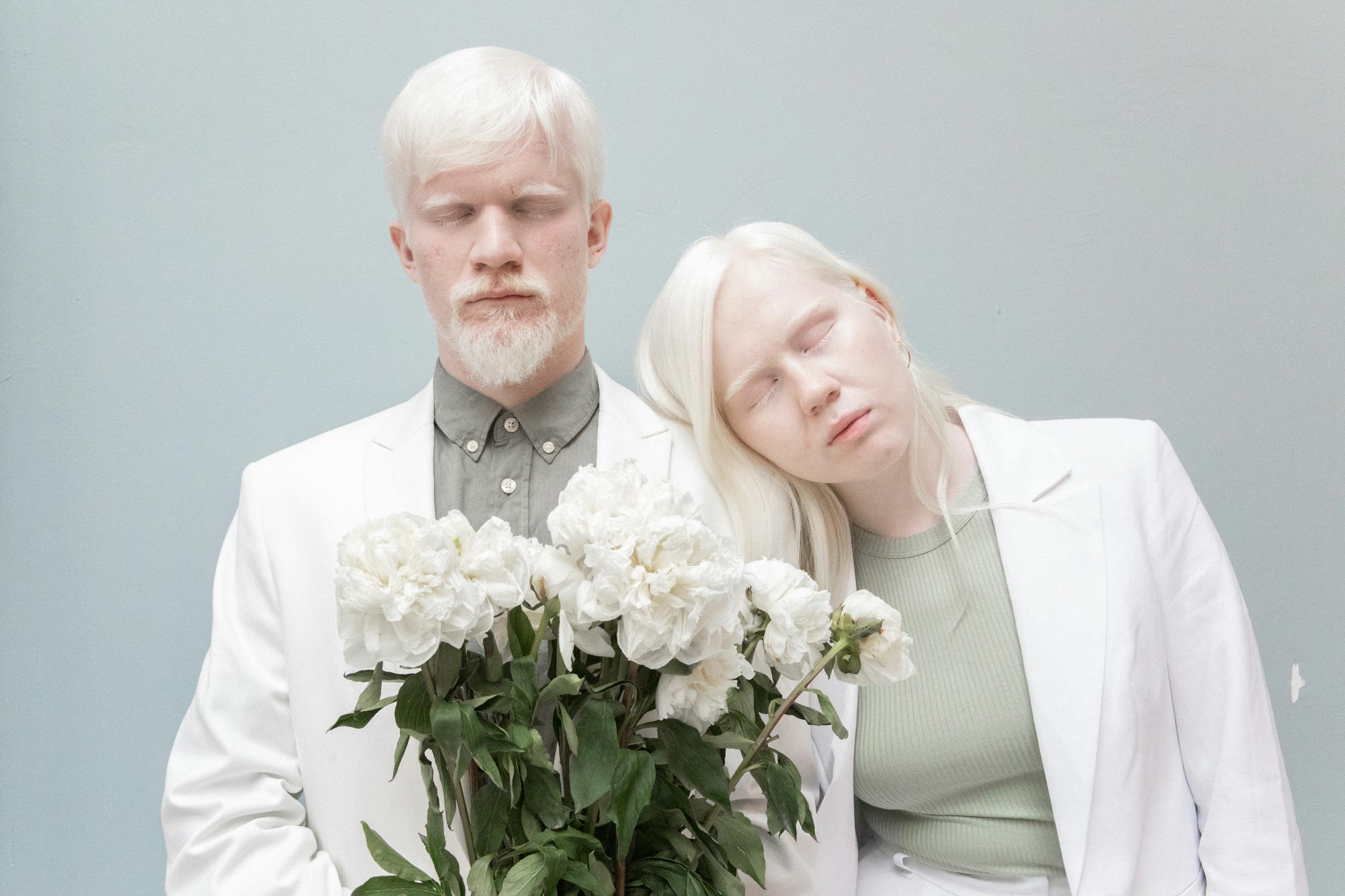Albino couple with closed eyes holding flowers · Free Stock Photo