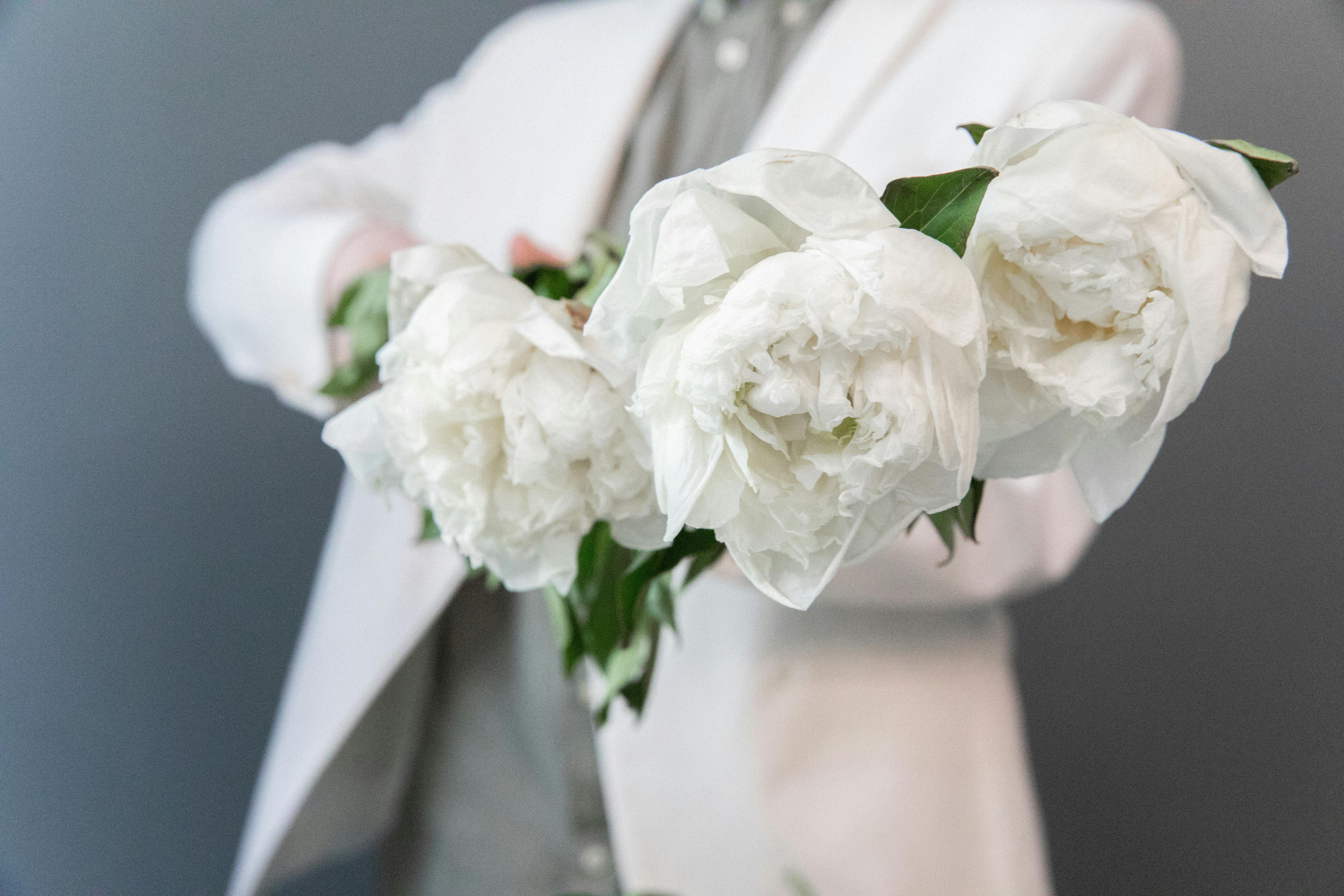 手持白花的西装特写，营造出优雅浪漫的氛围