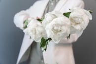 手持白花的西装特写，营造出优雅浪漫的氛围