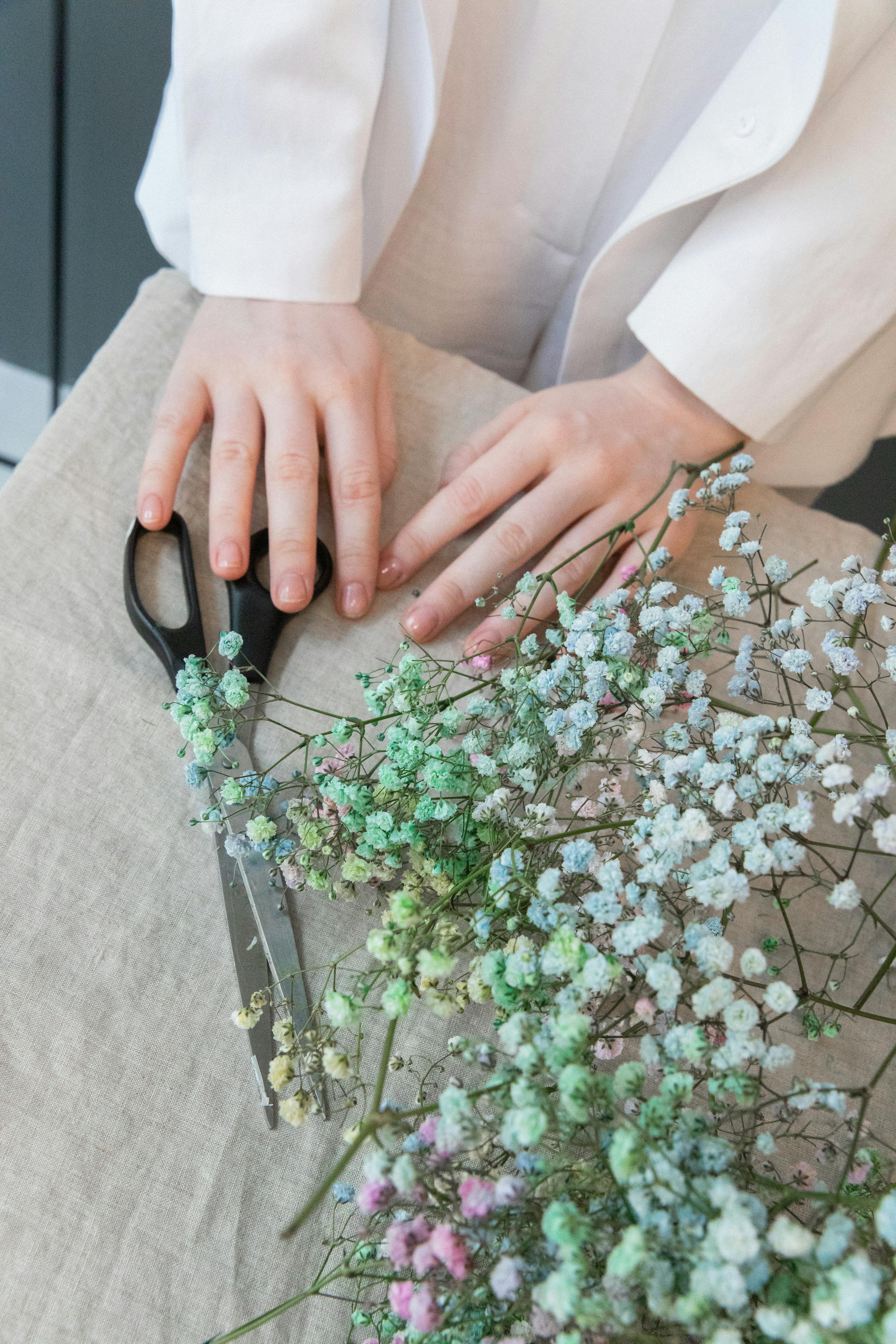 crop woman at table with flowers and scissors