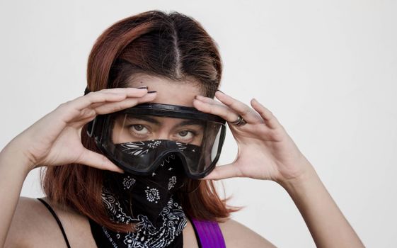 A woman confidently poses wearing protective goggles and a patterned bandana.