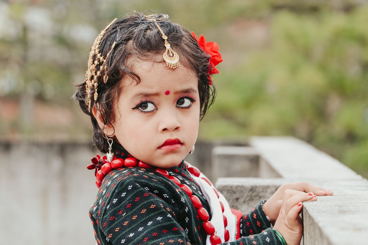 young girl in traditional attire with jewelry and makeup looking away