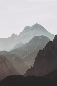 Serene view of misty mountains in the Dolomites with soft light and foggy atmosphere.