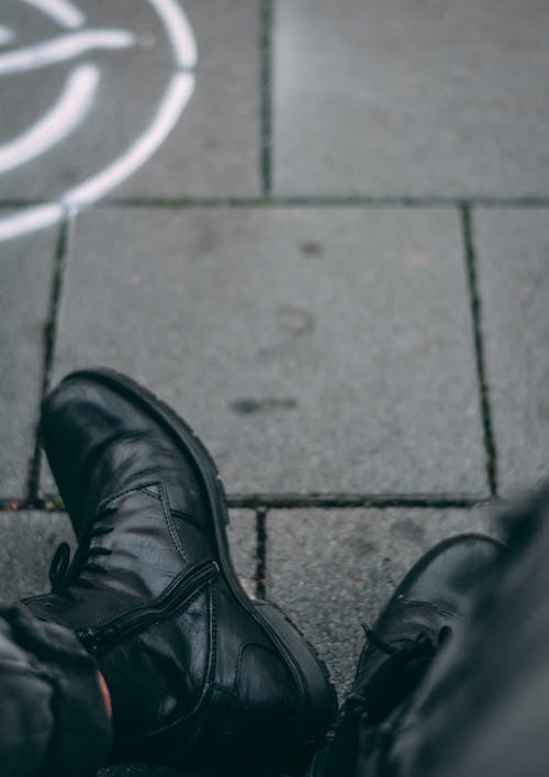 Close-Up Photo of a Person Wearing a Black Leather Shoes