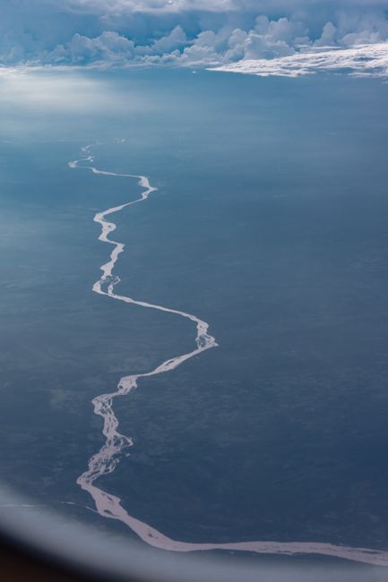 A breathtaking aerial view of a winding river with clouds in the background.