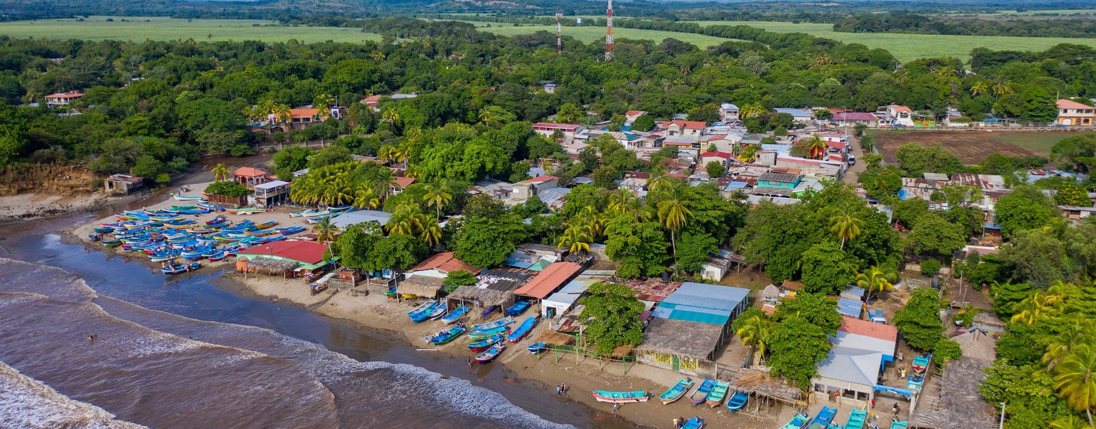Scenic aerial view of a vibrant coastal town in Nicaragua with colorful boats and lush greenery.