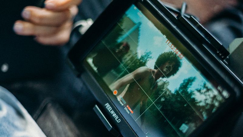 Close-up of a cinematic display showing a filmmaker at work capturing a scene outdoors.
