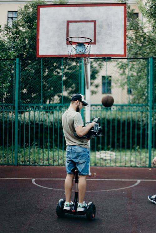 Man in Gray T-shirt and Blue Denim Shorts Holding Black Dslr Camera