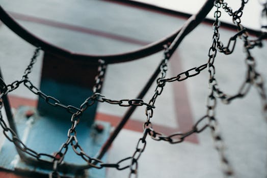 Close-up of a rustic basketball hoop with a chain net, capturing the essence of street sports.