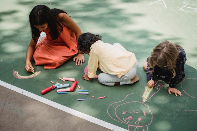 Children Drawing On Concrete With Chalk 