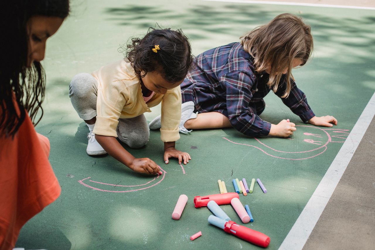 Children drawing with colourful chalk outdoors
