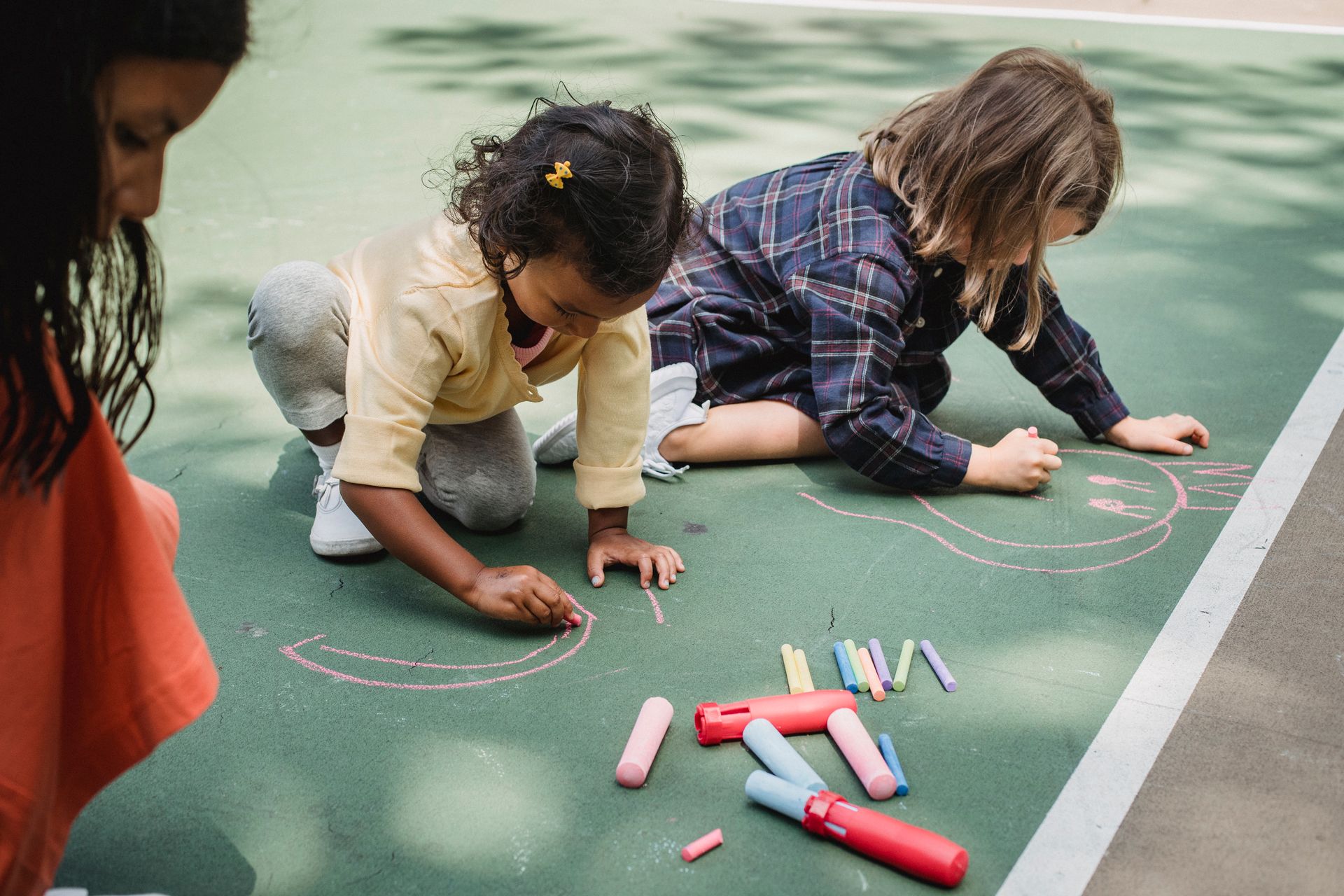 Children drawing together with colourful chalk outdoors