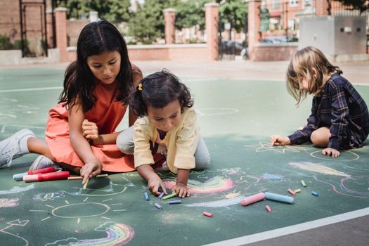 Children enjoying creative chalk art outdoors on a sunny day, fostering fun and imagination.