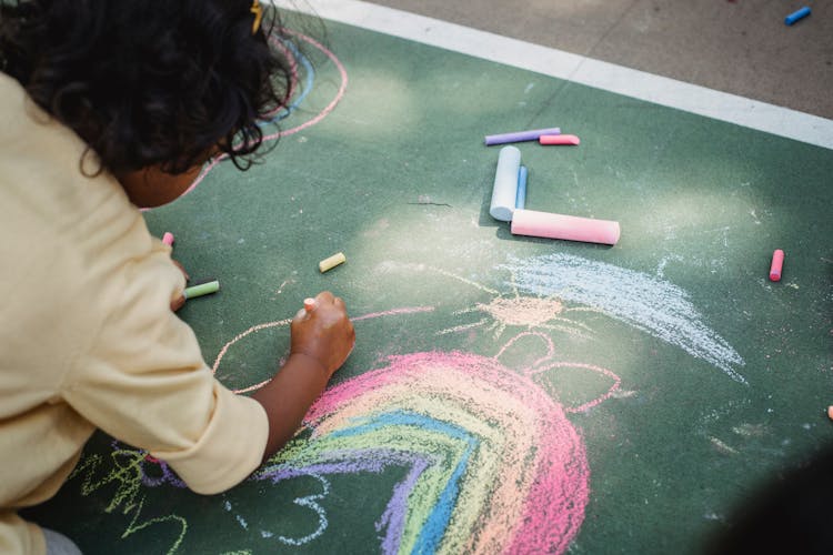 Close-up Of Child Drawing With Chalks On Ground