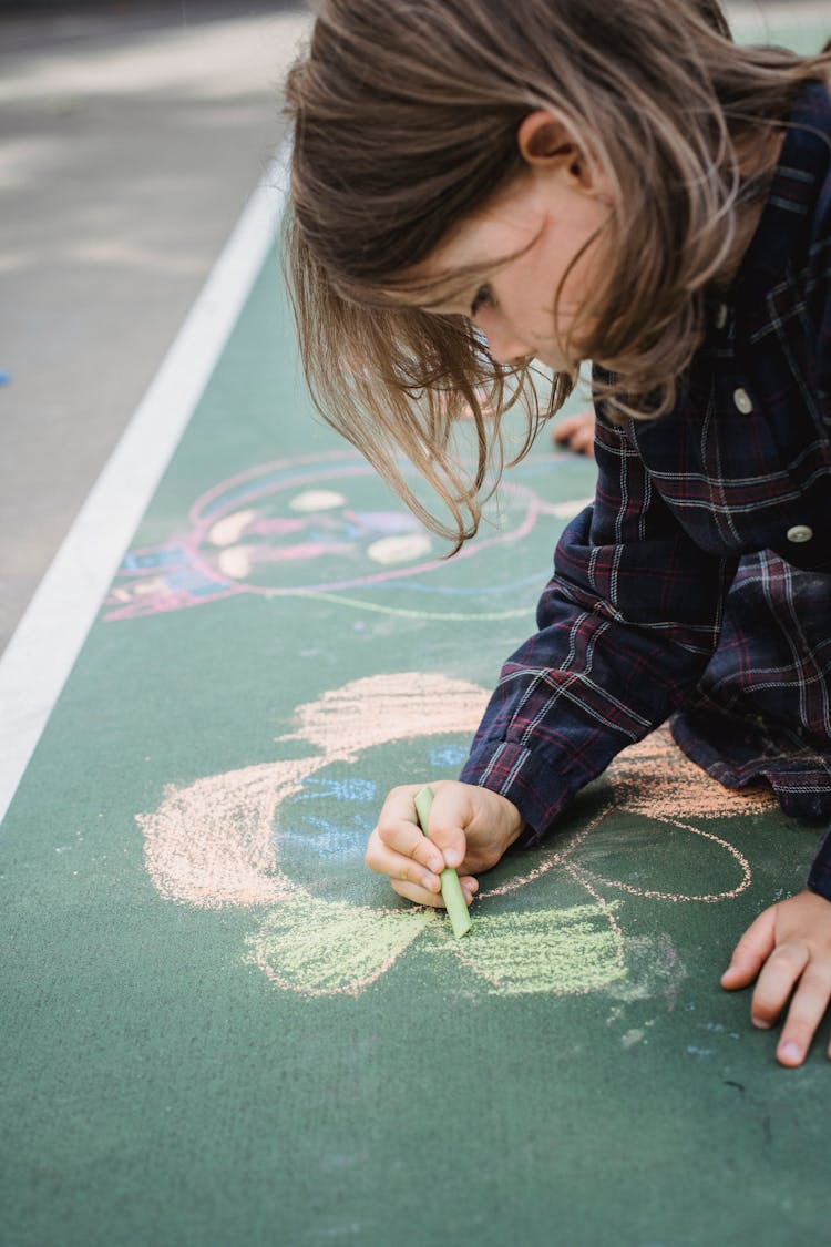 Kid Drawing A Flower With Chalk On Pavement