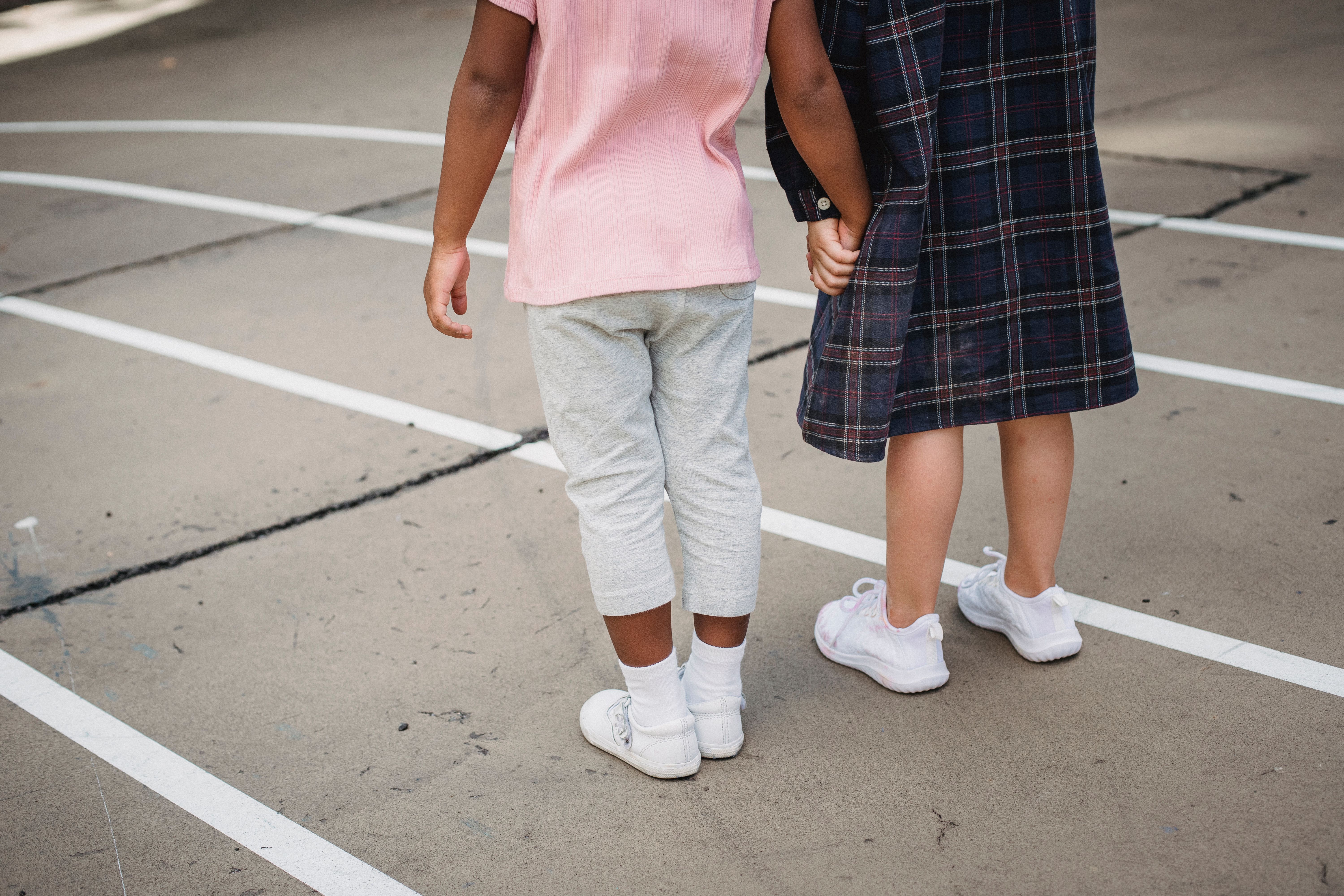 Two children holding hands on a playground, symbolizing friendship and diversity.