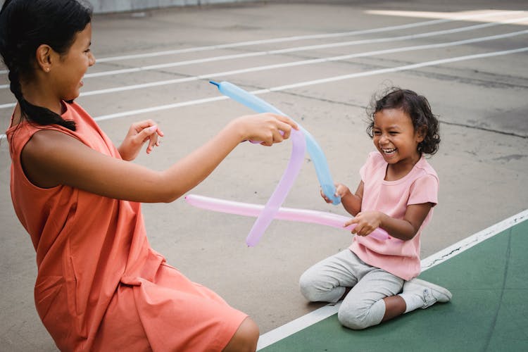 Smiling Girls Playing With Balloons Outside