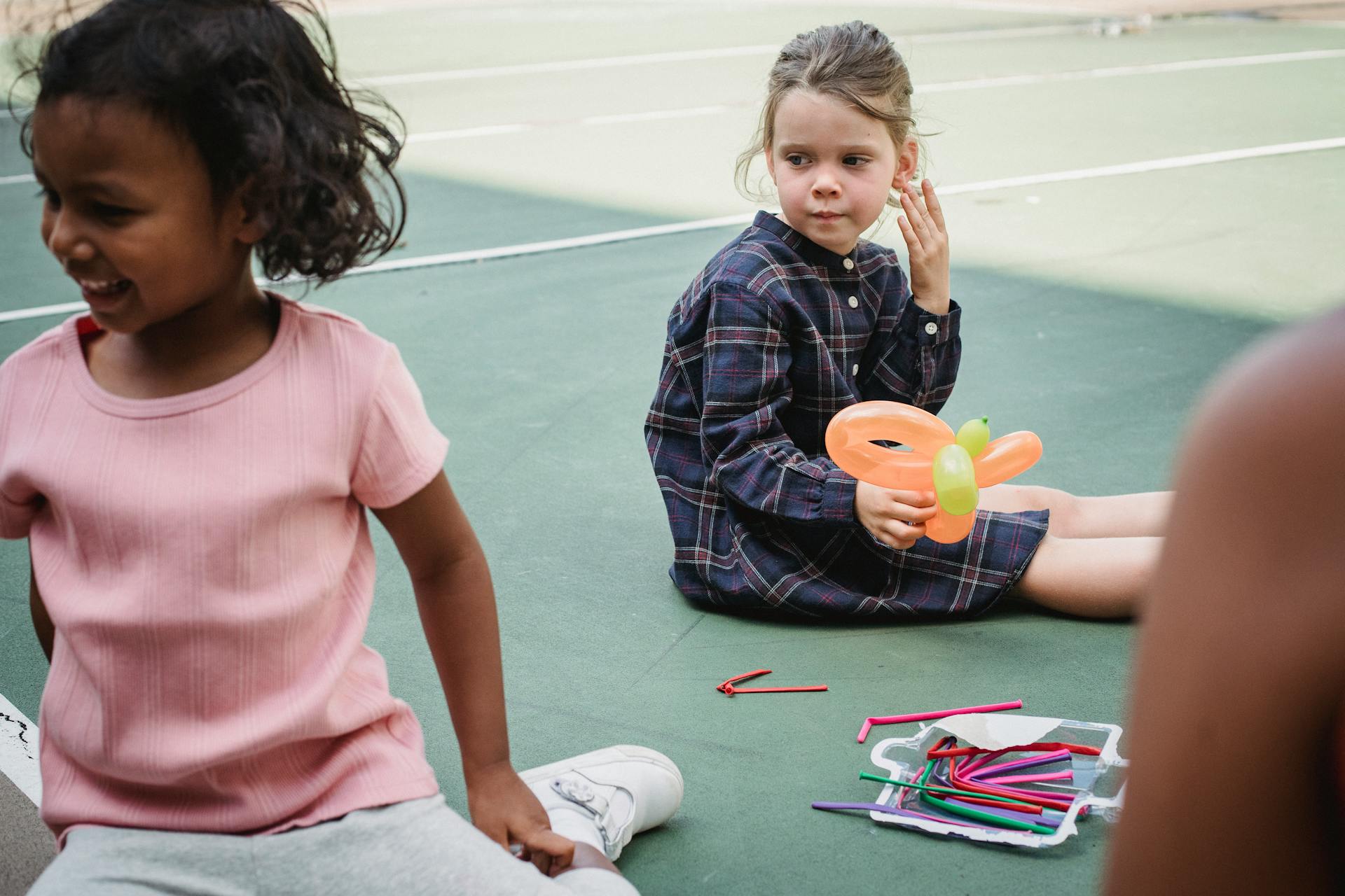 Children enjoying playtime with colorful balloon animals on a sunny day outdoors.